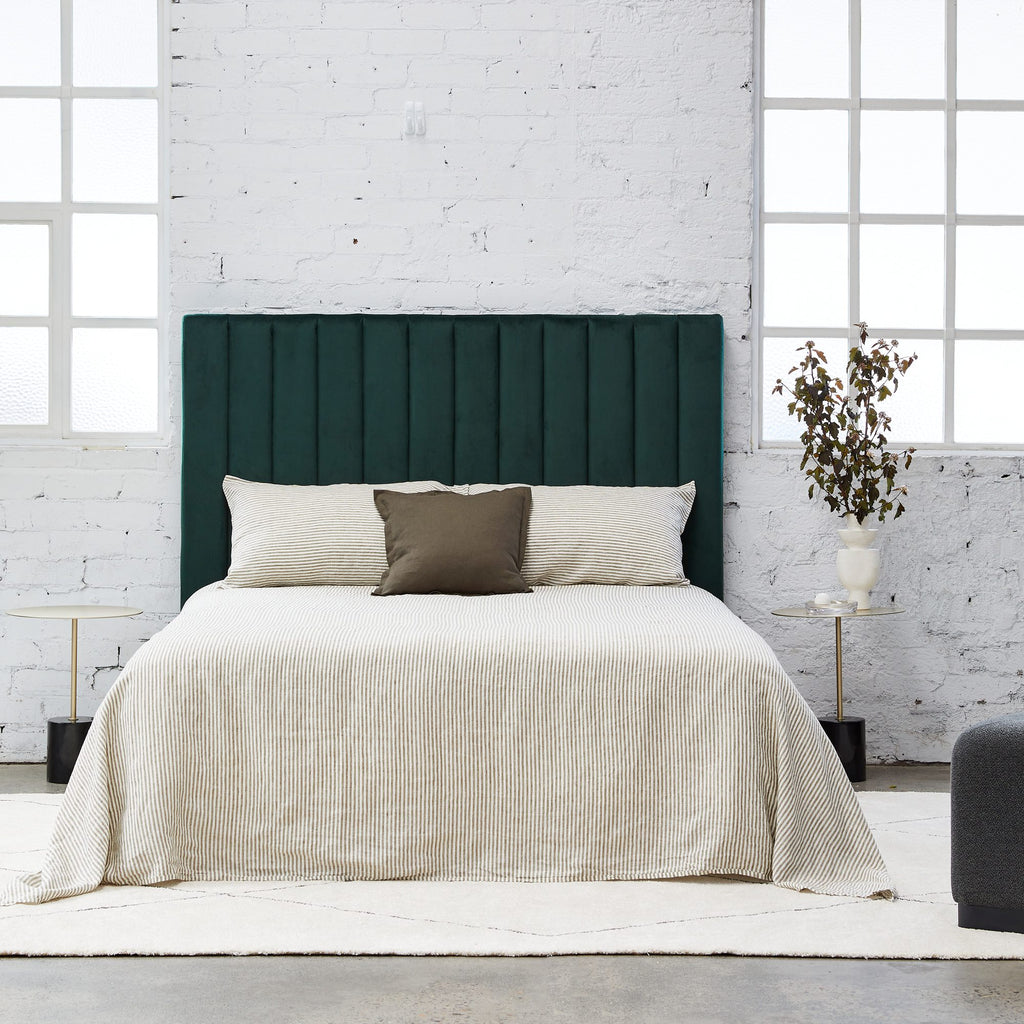 Free standing rectangular bedhead with padded panels fully upholstered in dark green velvet on a white background