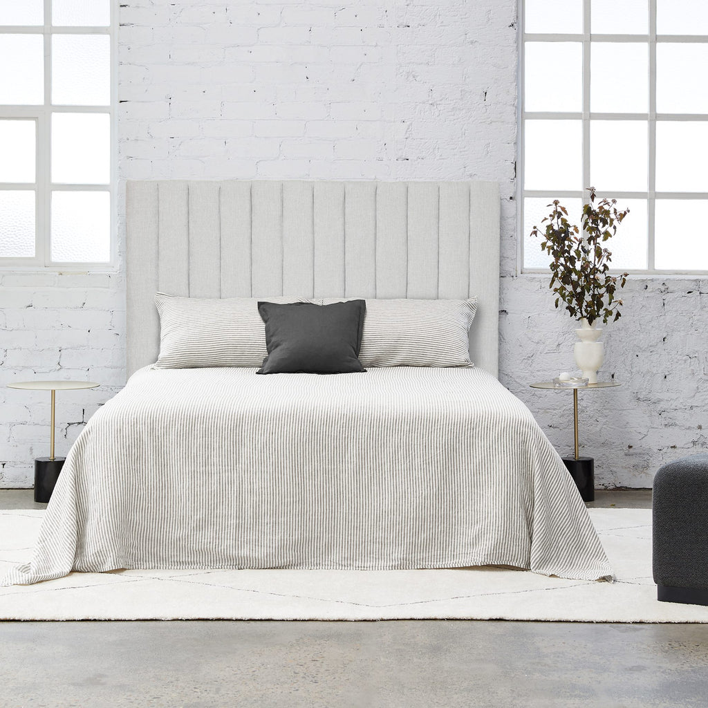 Modern square shaped bedhead made of panels fully upholstered in a light grey fabric on a white background