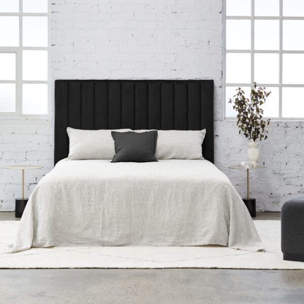 Modern square shaped bedhead made of panels fully upholstered in black velvet on a white background