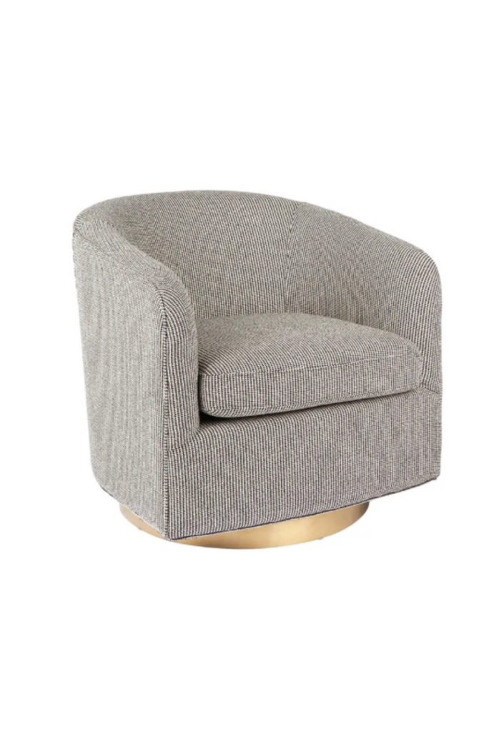 Tub style swivel armchair upholstered in a narrown black and white patterned viscose fabric with a gold round base on a white background