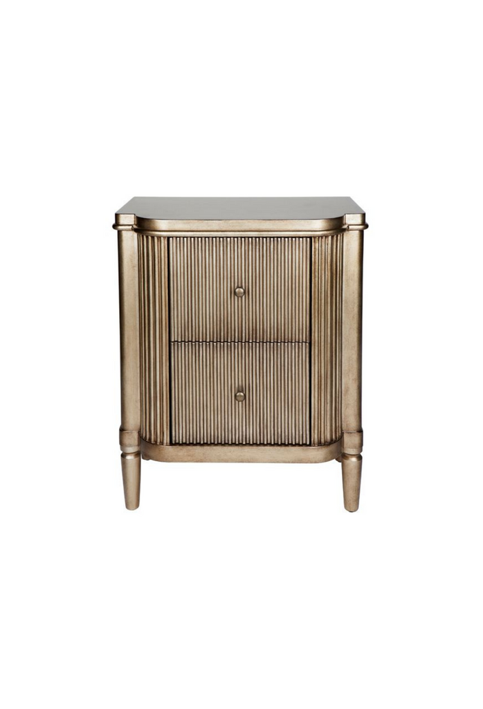 Art-deco style bedside table with round edges, a ribbed antique gold finish and two compact drawers on white background