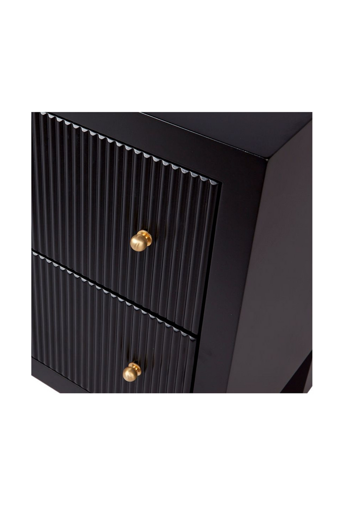 Black bed side table with two fluted drawers and brushed gold handles on a white background