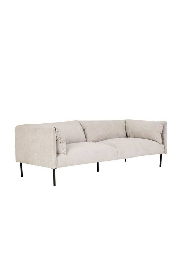 Modern 3 seater sofa with back and arm rests folded over upholstered in a cream fabric with thin cylindrical black metal legs