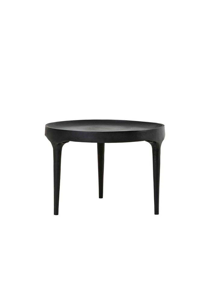Modern matt black aluminium coffee table with three long legs merging into a round concave table top on white background