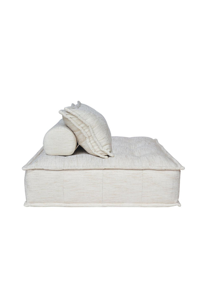 Square shaped lounger with button tufting fully upholstered in a natural off-white fabric with matching cushion on a white background