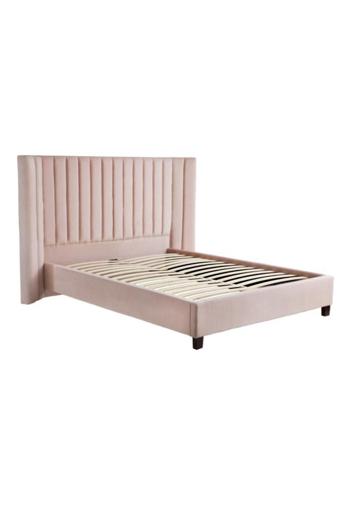 Blush pink velvet panelled bed with a large curved bedhead featuring plush velvet panels on a white background