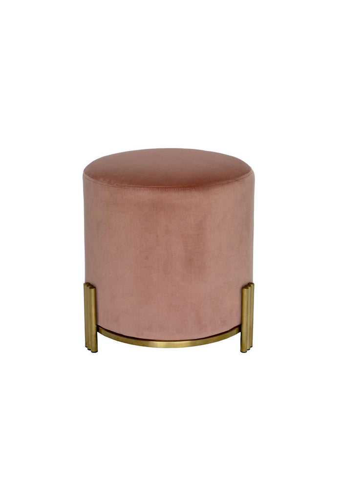 Round Ottoman upholstered in blush pink velvet with brushed gold metal base and three ribbed legs on white background