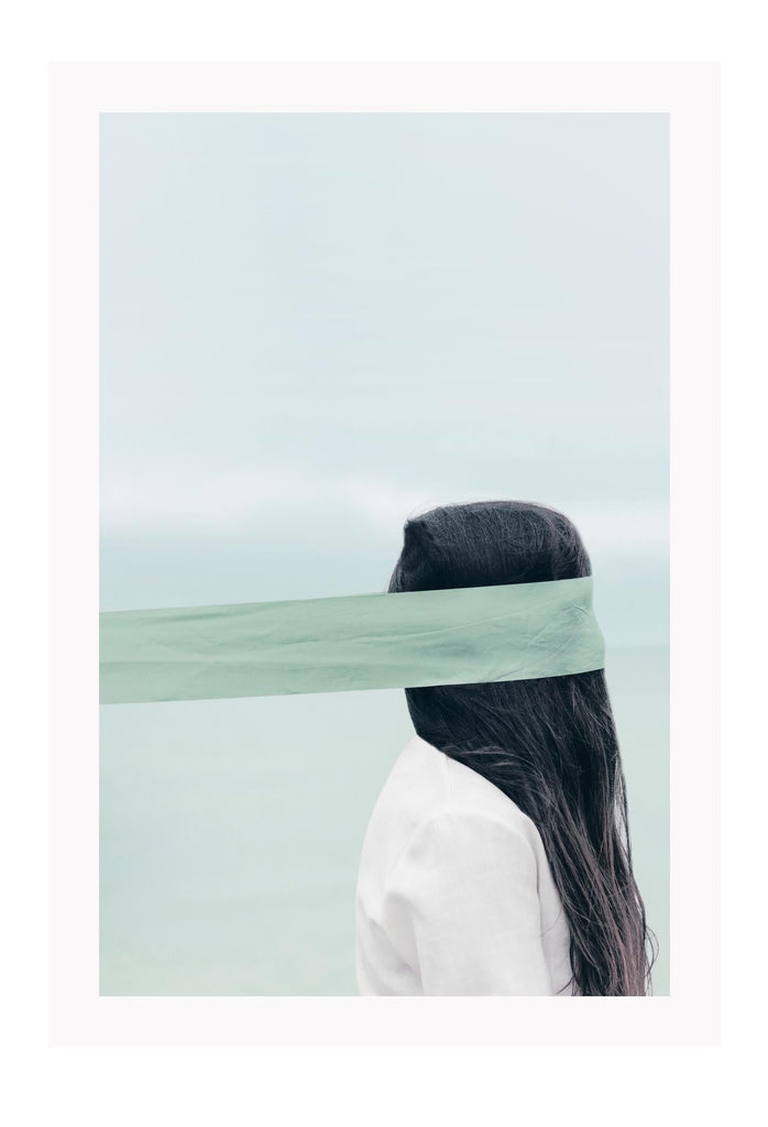 Photography of woman by the ocean wearing a blindfold with light blue tones and dark brown hair 