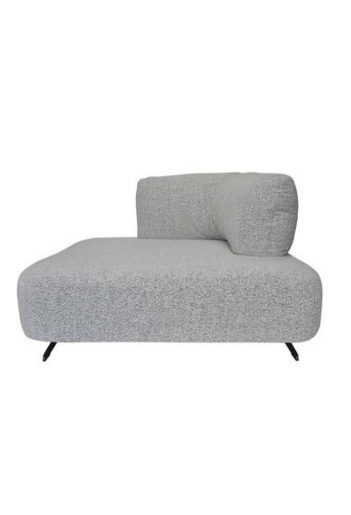 Modern corner lounger fully upholstered in grey boucle with matching corner cushion and black metal legs on white background