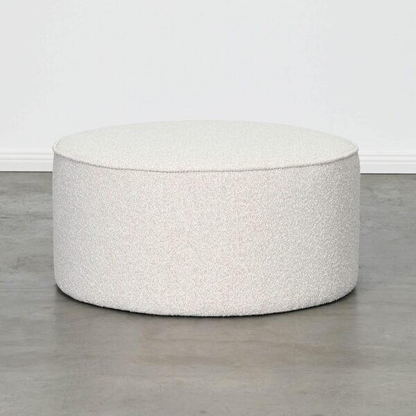Large Round Ottoman Fully Upholstered in Textured Ivory Oatmeal Coloured Fabric with Piped Edges on White Background