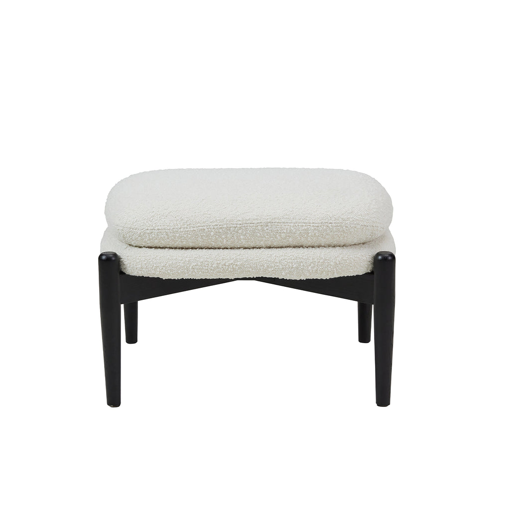 Ottoman stool with two piled up seating cushions in cream boucle and a crossed black wooden base on white background