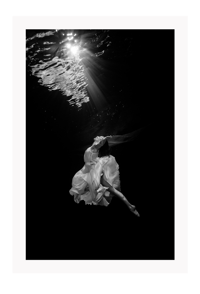 Black and white photography print with woman in ocean and white dress swimming 