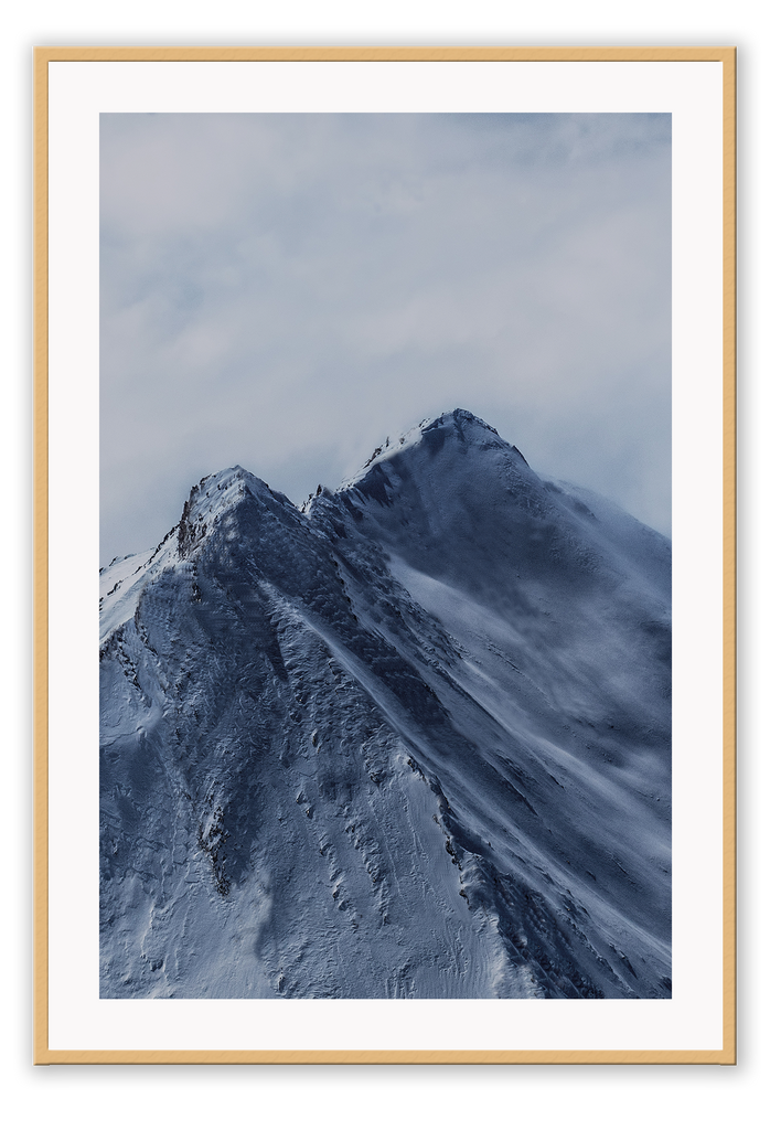 A natural wall art with blue snowy mountain close up and cloudy grey sky.  