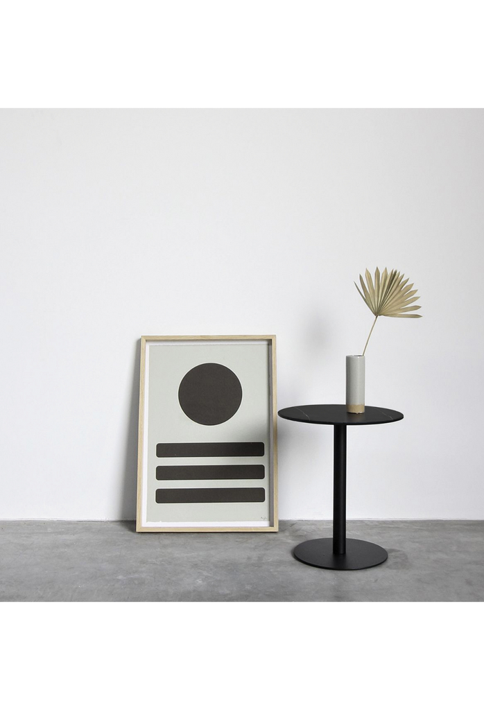 Petite round side table with a black marble top and a sturdy back metal base on a white background
