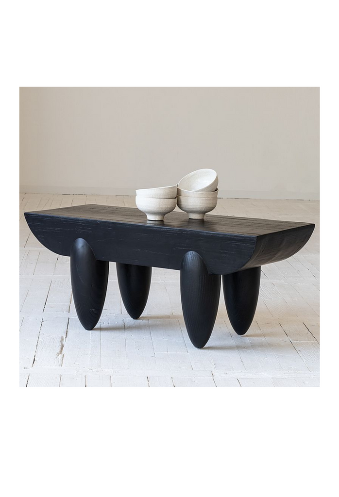 Hand crafted black pine coffee table with chunky curved table top and four oval shaped legs on white background