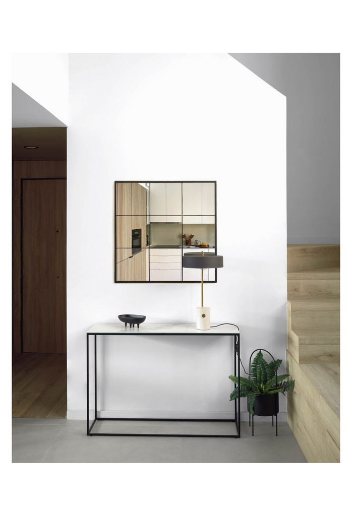 Minimalistic narrow console table with a rectangular white ceramic top and a thin black metal frame on a white background