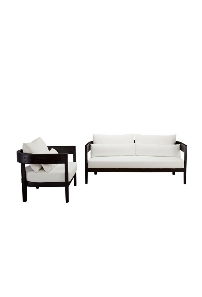Contemporary outdoor sofa with a black teak frame featuring a curved backrest and white cushions on a white background