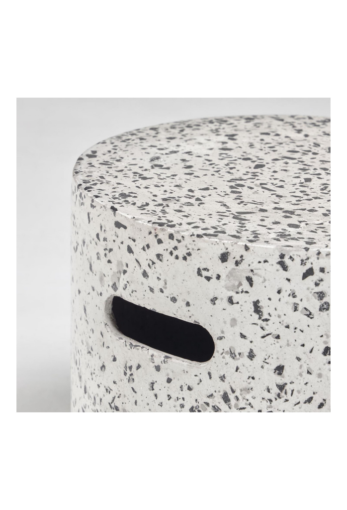 Minimalistic cylinder shaped stool in black and white terrazzo with two handles on a white background
