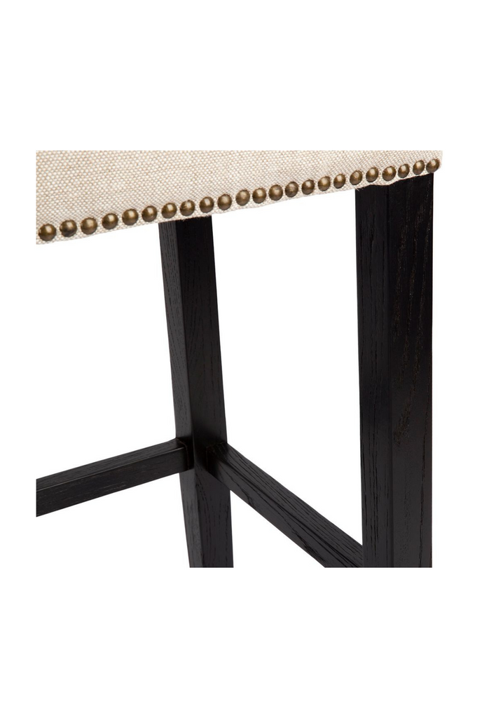 Black Bar Stool with Natural Linen Seat Cushion and Brass Stud Detailing on a white background