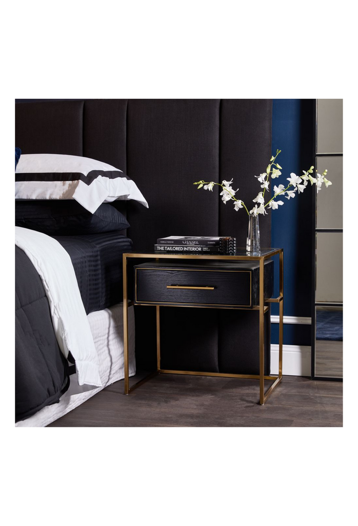 Modern Bedside Table with a Sleek Gold Steel Frame a slim black wooden Drawer and Glass Top on a white background