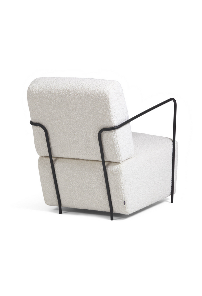 White boucle armchair with black metal frame and wire arm rests on a white background
