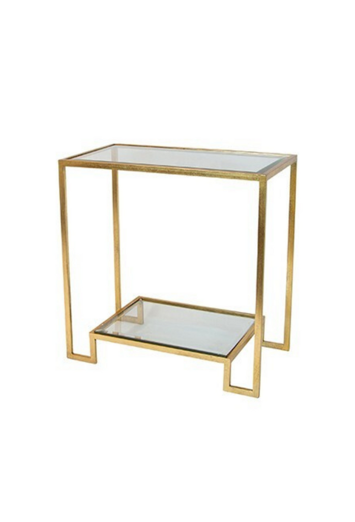 Modern geometric console with gold metal frame and two glass shelves with sharp edges on white background