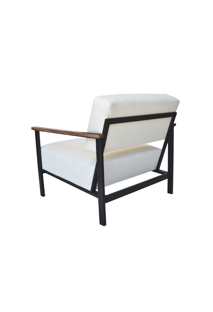 Contemporary armchair with a black metal frame, walnut wood arm rests and cream white textured upholstery on a white background