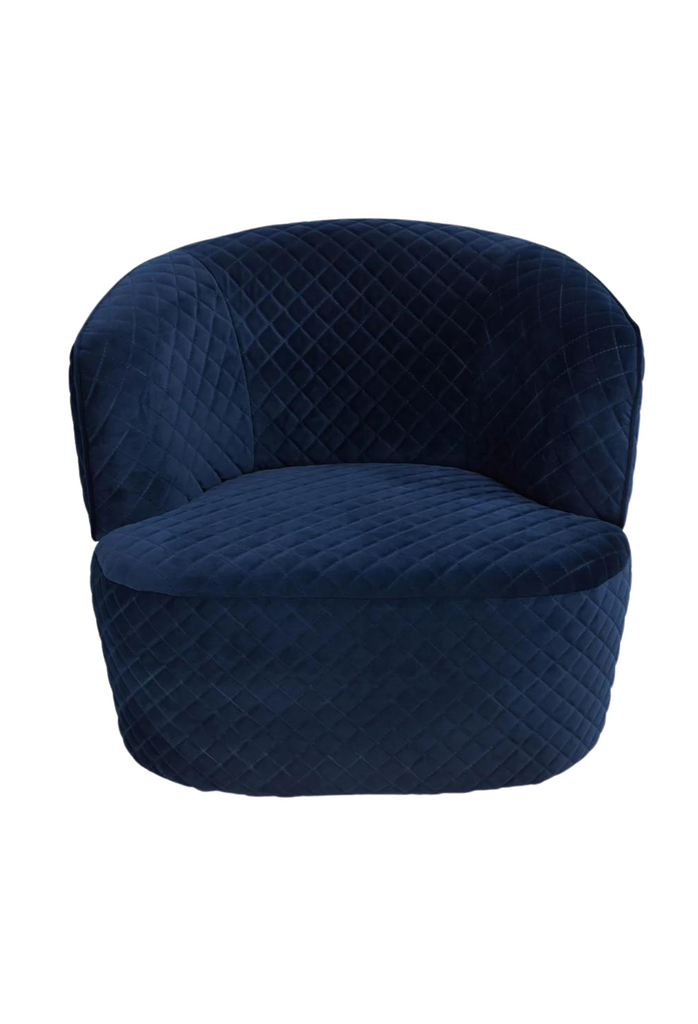 Chunky quilted tub-style armchair fully upholstered in navy blue velvet with curved back and arm rest on a white background