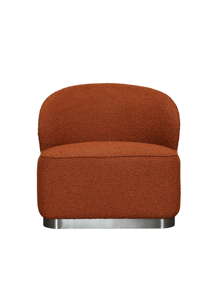 Chunky armless chair with curved back rest fully upholstered in a rust brick coloured boucle with a solid dark grey metal base