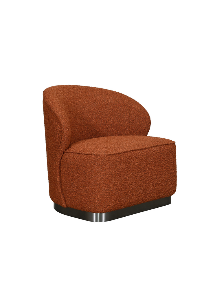 Chunky armless chair with curved back rest fully upholstered in a rust brick coloured boucle with a solid dark grey metal base