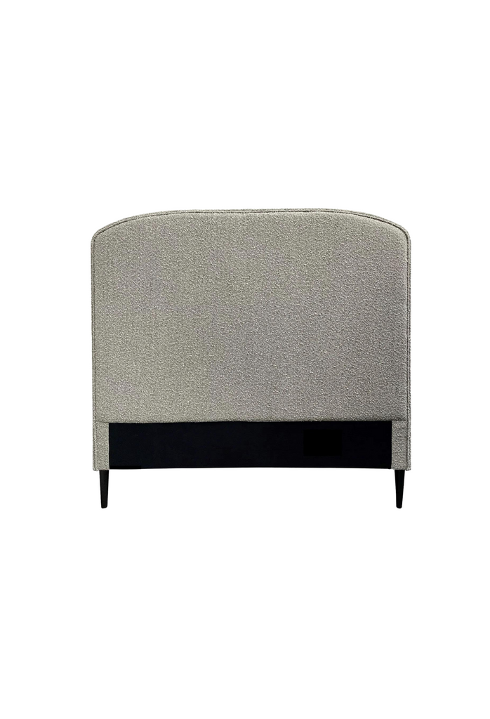 Minimalistic bedhead fully upholstered in wheat beige boucle with round edges and two black feet on white background