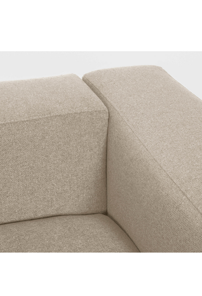 Modern 2 seater in clean geometric shape with sharp edges and one large seat cushion fully upholstered in a beige fabric