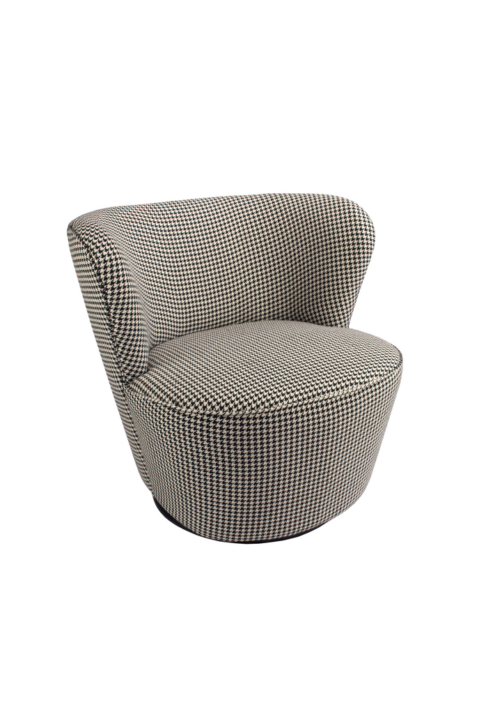 Petite swivel chair with wide curved backrest fully upholstered in a houndstooth patterned fabric on an almost hidden black metal base