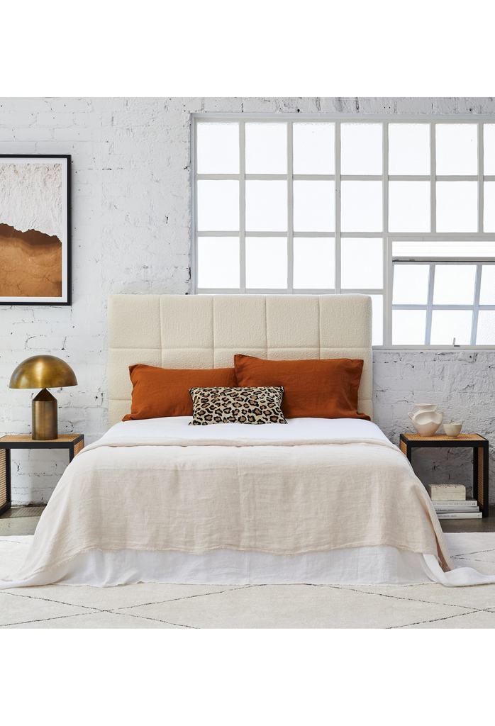 Modern padded bedhead fully upholstered in cream boucle with square shaped stiching details on a white background