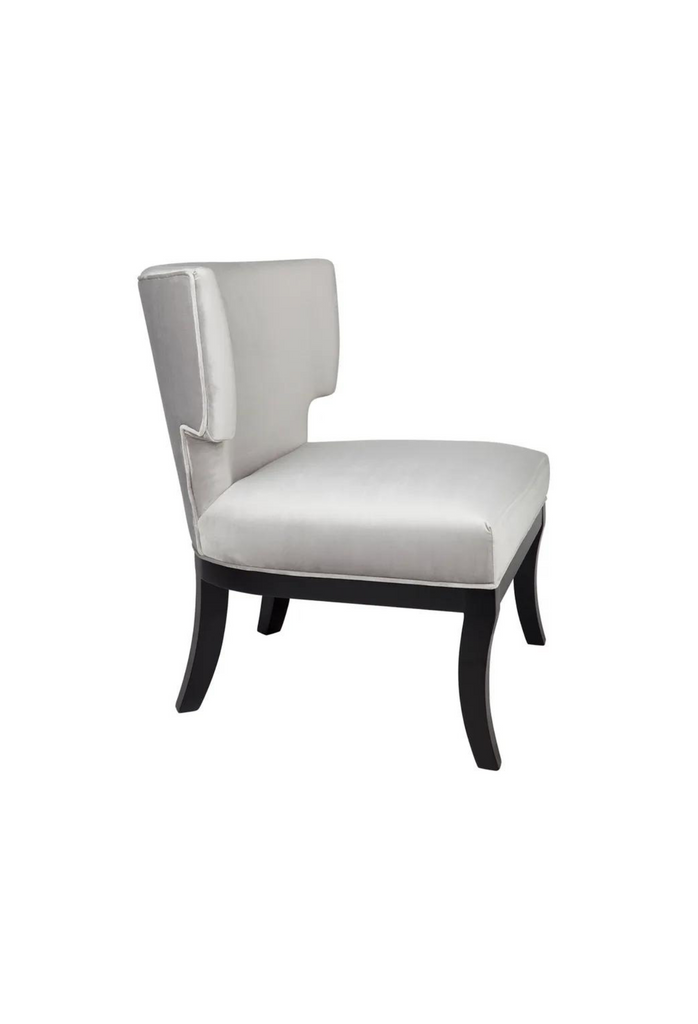 Contemporary wingback-style occassional armchair with a curved backrest upholstered in silver velvet with a black frame and legs