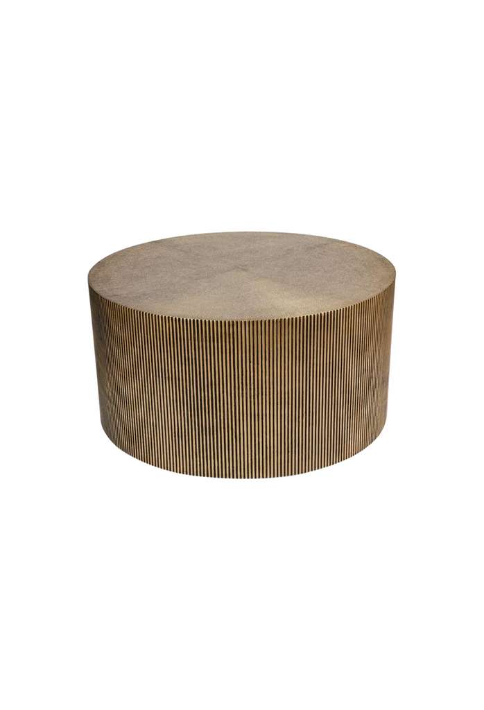 Solid round coffee table with fluted base in brass and antique gold tones on a white background