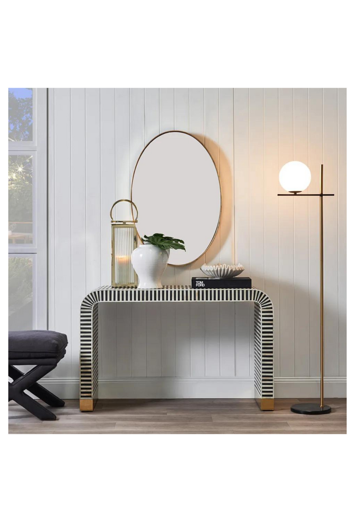 Modern curved console table with black bone inlay creating black and white striped look and brass clad base