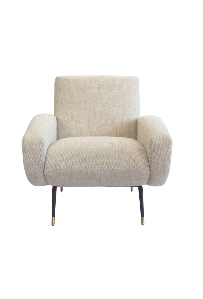 Natural linen armchair with two chunky arm rests featuring round edges and four slim black metal legs with brass finish cups
