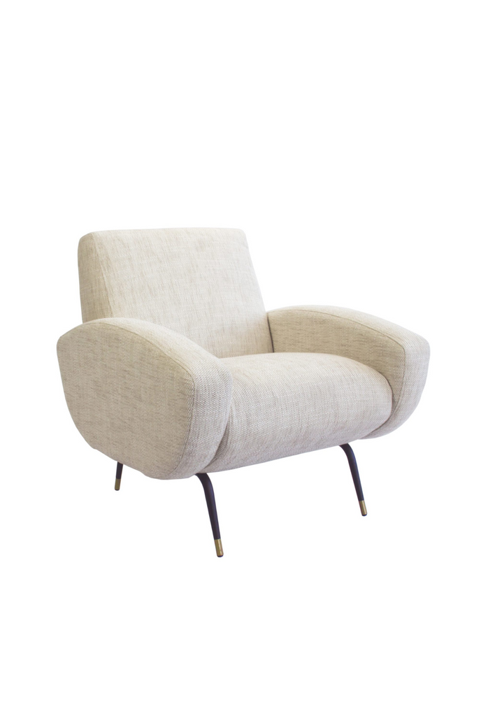Natural linen armchair with two chunky arm rests featuring round edges and four slim black metal legs with brass finish cups