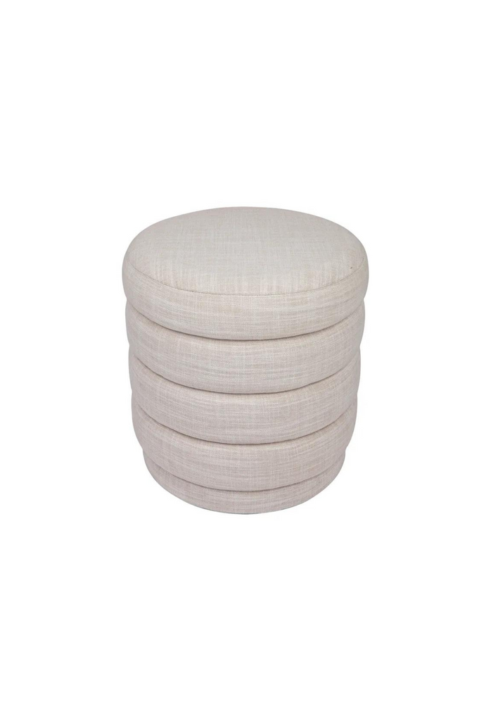 Petite round ottoman with four padded layers and an upholstered base all upholstered in off-white linen on white background