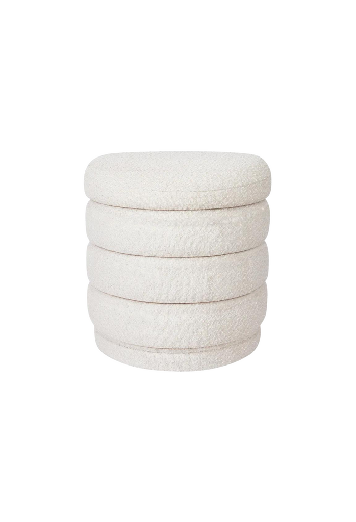 Petite round ottoman with four padded layers and an upholstered base all upholstered in white boucle on white background