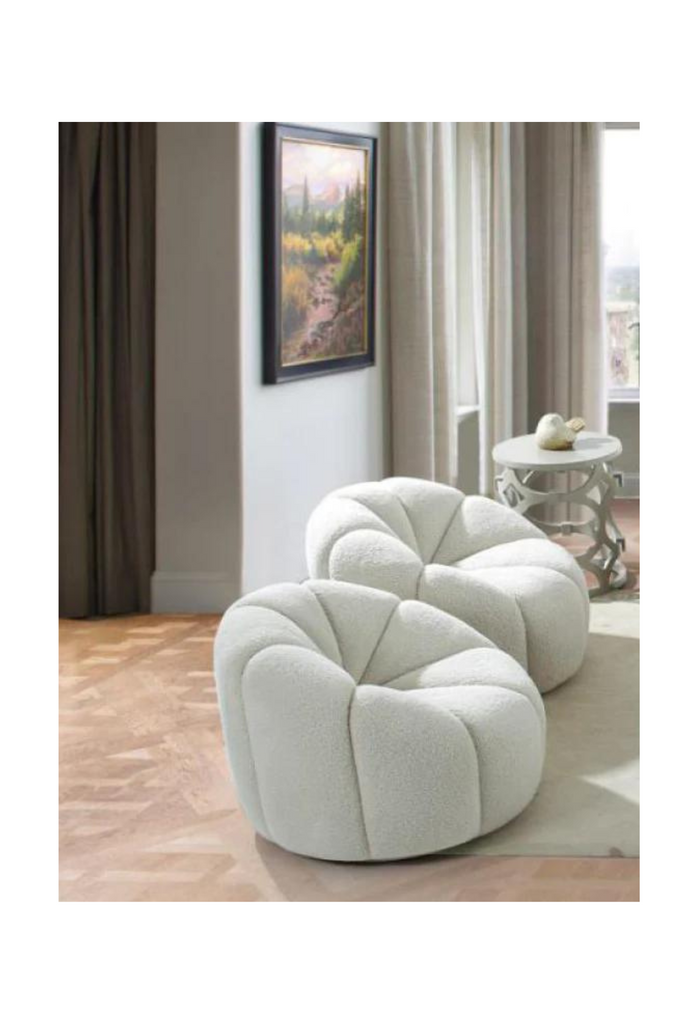 Compact armchair fully upholstered in a white wool like fabric with stitchings coming from the outside and connecting in the middle of the seat