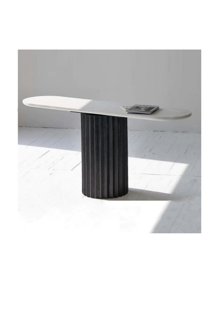 Console with a round black fluted base and an oval white table top in concrete finish on white background