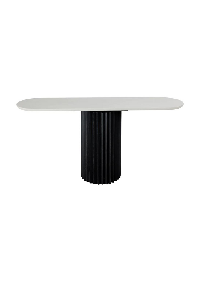 Console with a round black fluted base and an oval white table top in concrete finish on white background