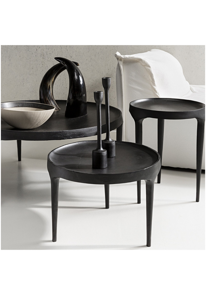 Modern matt black aluminium coffee table with three long legs merging into a round concave table top on white background