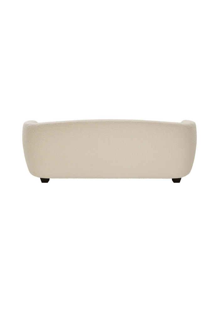 Modern minimalistic sofa in a slightly curved shape fully upholstered in cream boucle with black feet on white background