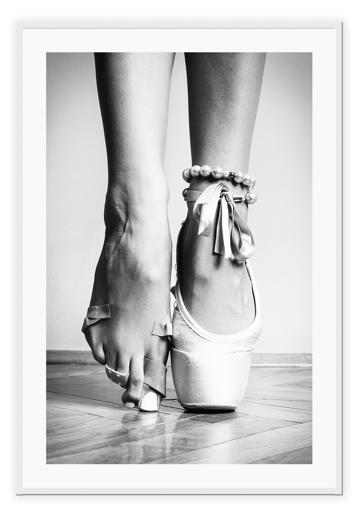 A vintage black and white wall art with a ballerina in point shoes close-up