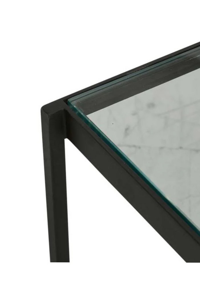 Modern rectangular coffee table with sharp edges and a black metal frame, a glass top and a white marble bottom shelf