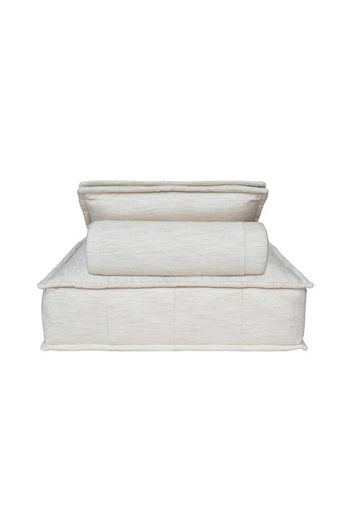 Square shaped lounger with button tufting fully upholstered in a natural off-white fabric with matching cushion on a white background