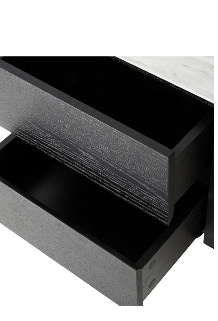 Black cubic beside table with round edges a white ceramic top and two drawers on a white background
